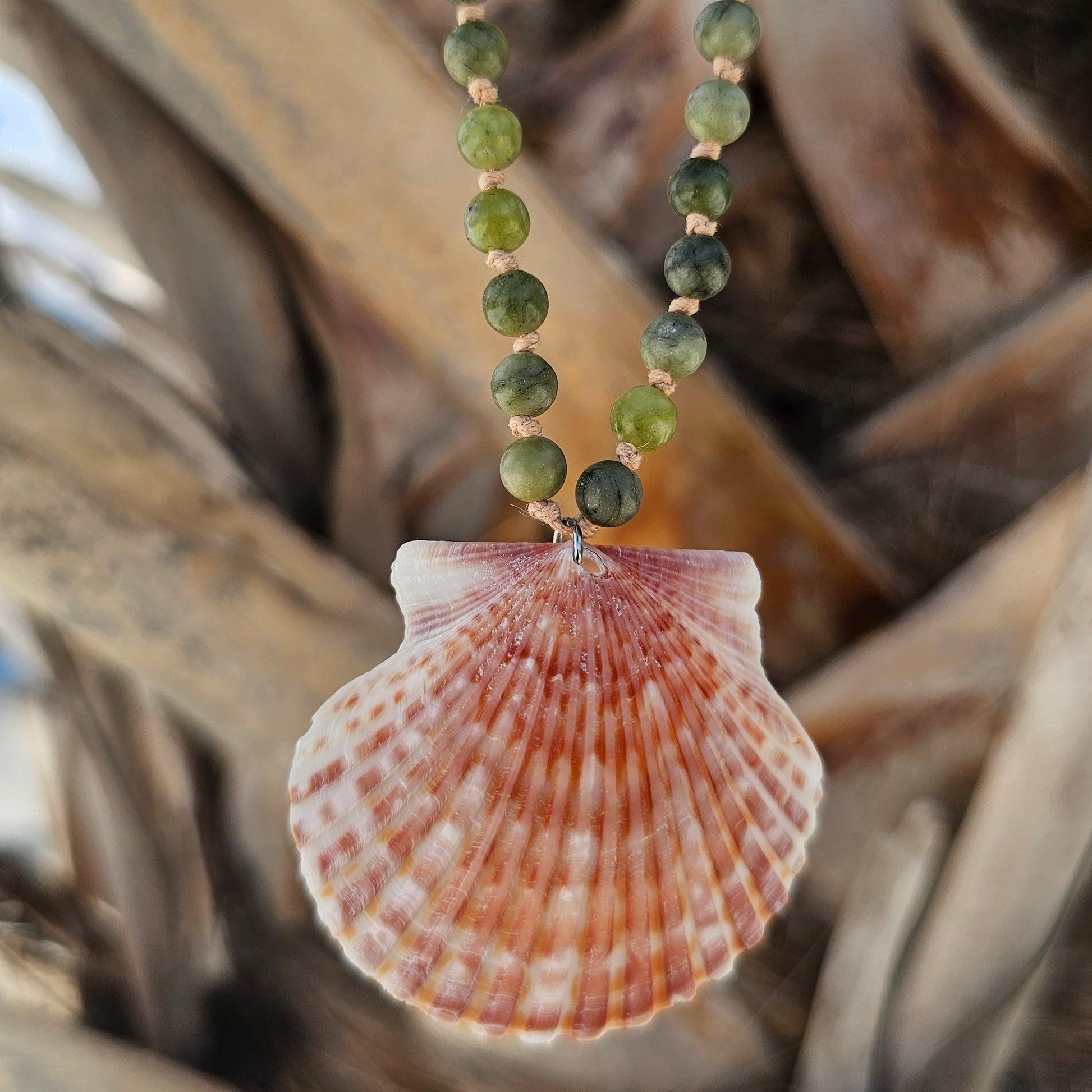 Necklace with green beads and a shell pendant on a natural background