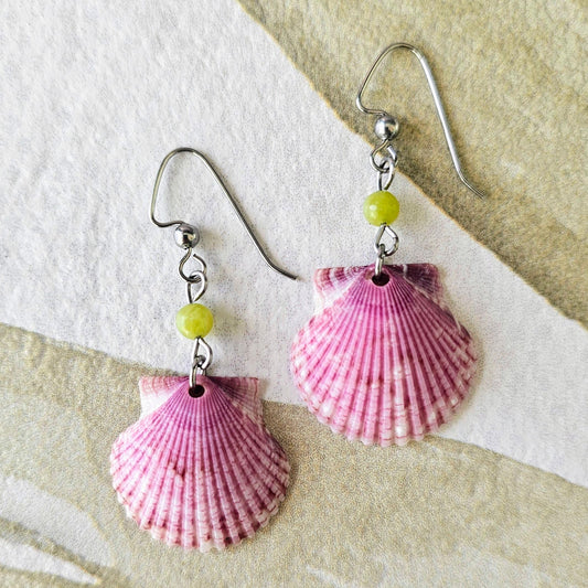 Shell-shaped earrings with pink and red patterns on a textured surface